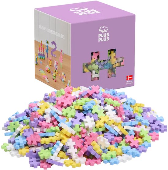 Een doos met Plus Plus Mini pastelkleurige bouwstenen en een hoopje van de stenen ernaast.