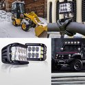 Zwarte LED-lamp met acht reflectoren en vier oranje LED's, naast een bouwmachine in de sneeuw en een Jeep.
