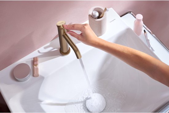 Gouden Hansgrohe wastafelkraan met een hendel, water stroomt in de wasbak.