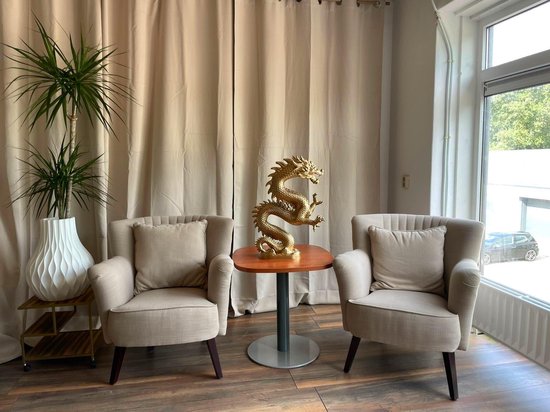 Gouden drakenbeeld met een kronkelende staart, schubben en een gedetailleerde kop, staand op een houten tafel.
