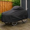 Zwarte universele cargo hoes over een bakfiets, buiten op een betegeld terras.