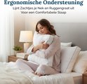 Een vrouw in een lichtroze pyjama zit op een bed en knuffelt een wit kussen. Ze heeft haar ogen gesloten en glimlacht.