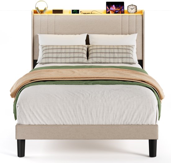 Een volledig opgemaakt beige gestoffeerd bed met kussens, plaids en een verlicht hoofdbord met opbergruimte.