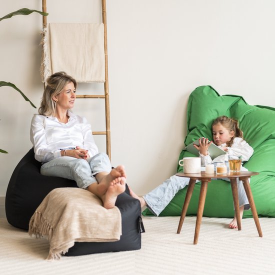 Une femme assise sur un pouf noir, une fille sur un pouf vert.