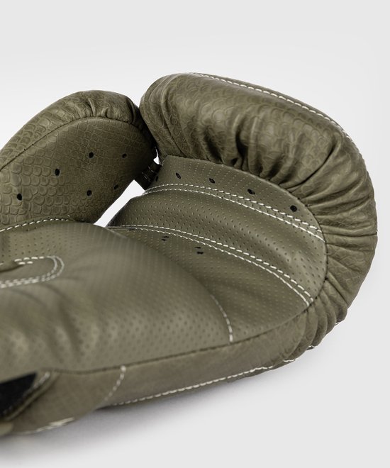 Twee legergroene bokshandschoenen met schubbenpatroon en witte stiksels, vanuit een laag perspectief gezien.