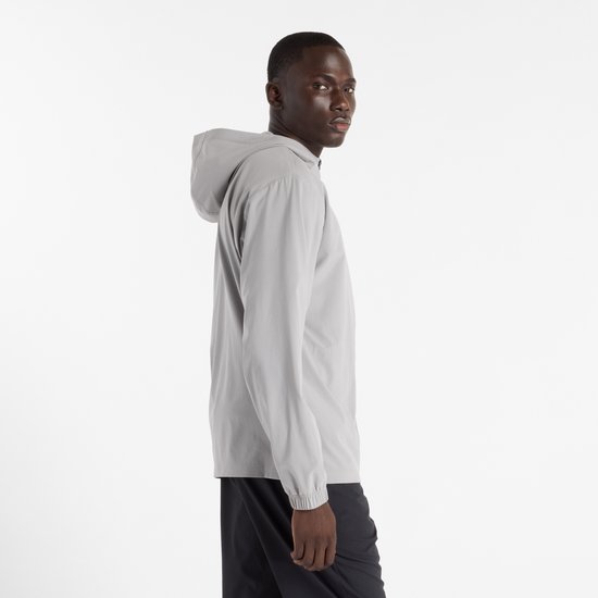Man in grijze New Balance sportjas met capuchon, zij-aanzicht.