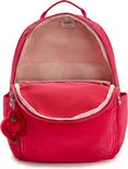 Sac à dos Kipling rouge ouvert avec doublure rose, des tons beiges et un porte-clés singe rouge.