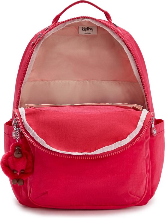 Sac à dos Kipling rouge ouvert avec doublure rose, des tons beiges et un porte-clés singe rouge.