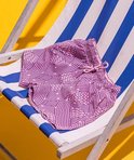 Paarse zwembroek met golvend patroon, liggend op een blauw-wit gestreepte strandstoel.