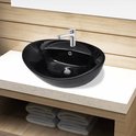 Lavabo ovale noir avec robinet chromé sur un comptoir, avec des serviettes sur une étagère.