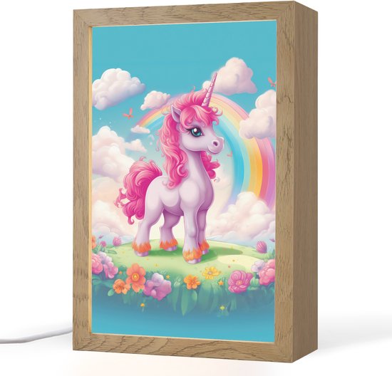 Een roze eenhoorn met een regenboog en wolken op een veldje met bloemen, in een houten lijst.