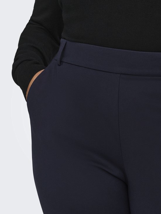 Detail van de donkerblauwe broek met insteekzakken en riemlus.