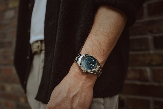 Man draagt zilverkleurig Edifice horloge met blauwe wijzerplaat om de pols.