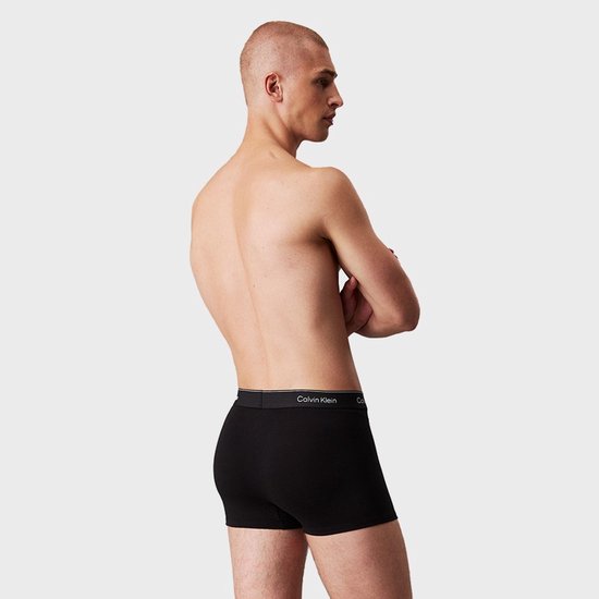 Man met een zwarte Calvin Klein boxer, van achteren gezien.