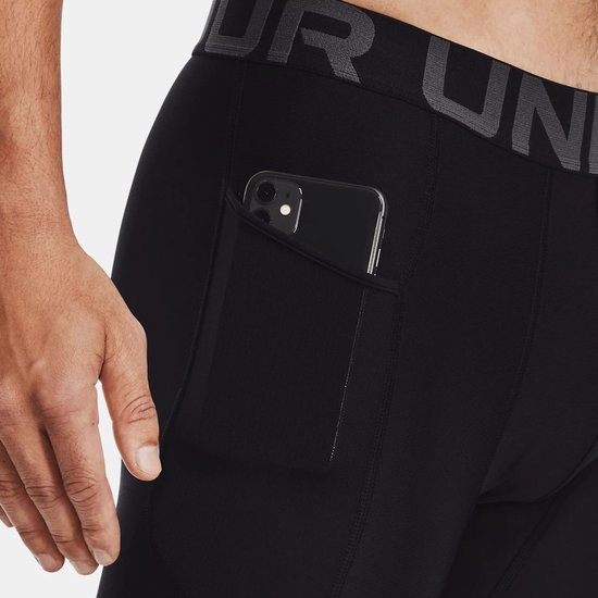 Detail van een zwarte sportlegging voor heren met een telefoon in het zijvak. Zwarte tailleband met grijze tekst.