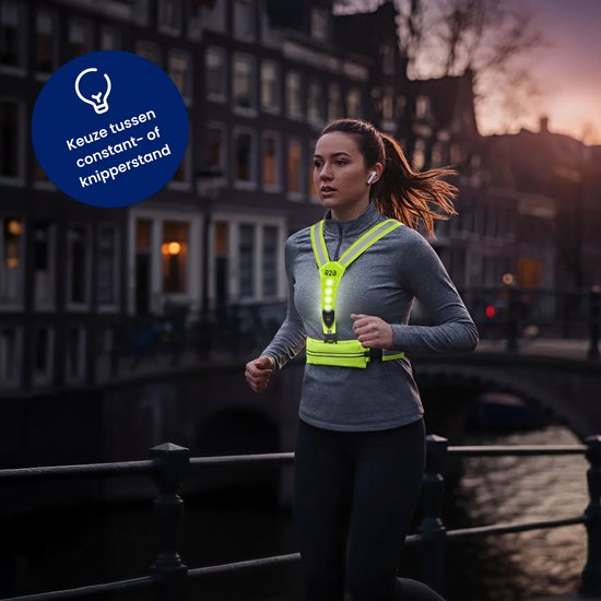 Vrouw rent 's avonds in de stad met een neongeel R2B hardloopvest met LED-verlichting.