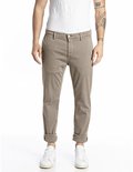 Mannelijke chino in beige met opgerolde broekspijpen en witte sneakers.