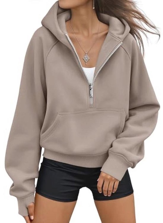 Vrouw in beige cropped hoodie met open rits, witte top eronder en zwarte fietsbroek.