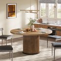 Ronde houten eettafel met geribbeld onderstel, gedekt voor vier personen.