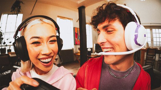 Vrouw en man met witte JBL gaming headsets die samen lachen en gamen.
