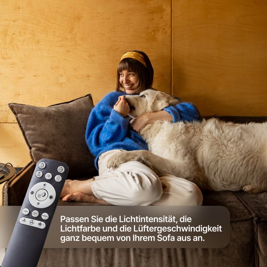 Vrouw knuffelt hond op bank, met afstandsbediening; past licht en ventilator aan.