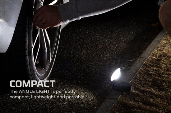Kleine Nebo werklamp op een stoeprand, verlichtend naast een autoband.