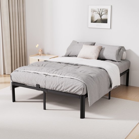 Cadre de lit en métal noir avec draps et coussins gris.