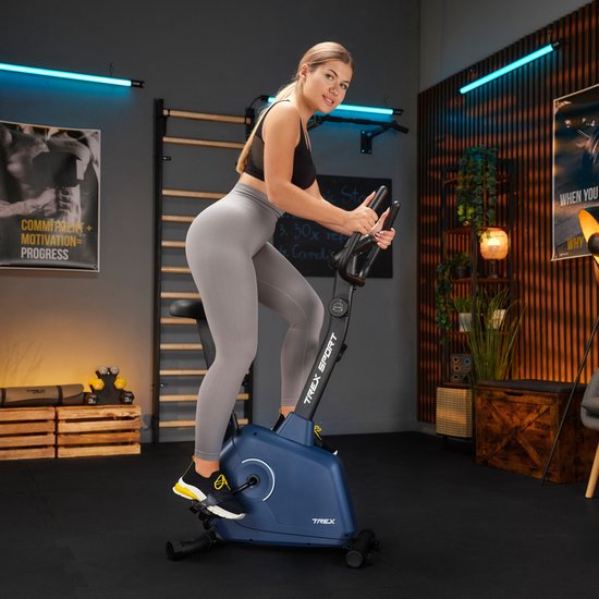 Vrouw op een marineblauwe hometrainer met 'TREX SPORT' logo in een fitnessruimte.