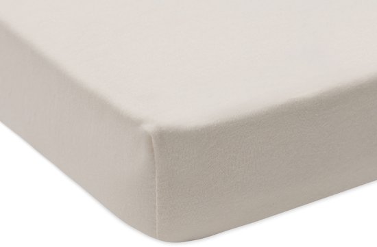 Hoek van een crèmekleurig jersey hoeslaken voor een boxmatras.
