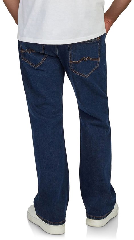 Achterkant van een man in donkerblauwe bootcut jeans met oranje stiksels en witte sneakers.