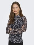 Model draagt longsleeve met hoge hals, abstracte print in nachtblauw en beige, armen gekruist.