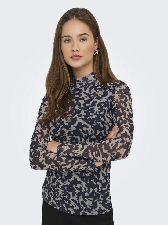Model draagt longsleeve met hoge hals, abstracte print in nachtblauw en beige, armen gekruist.