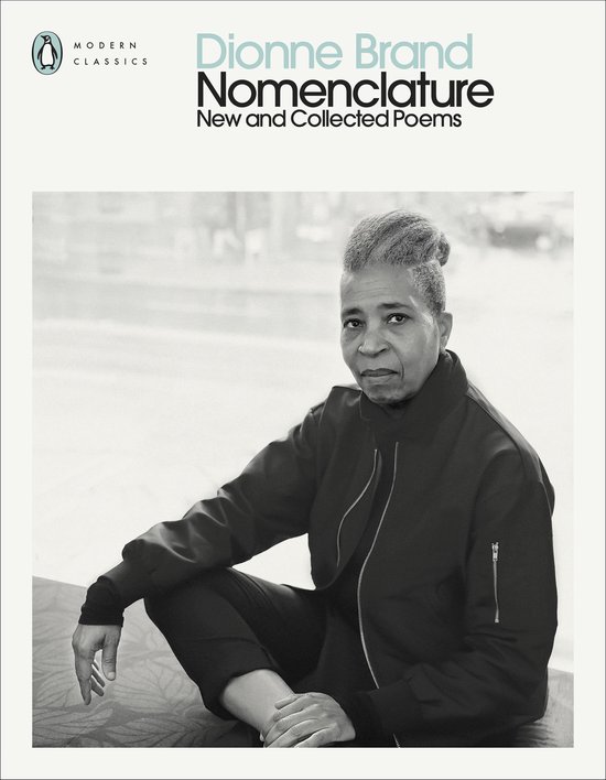 Dionne Brand, Nomenclature: New and Collected Poems, Modern Classics. Een zwart-witfoto van Dionne Brand, die met gekruiste benen op een bank zit, een zwarte bomberjack en een zwarte broek draagt.
