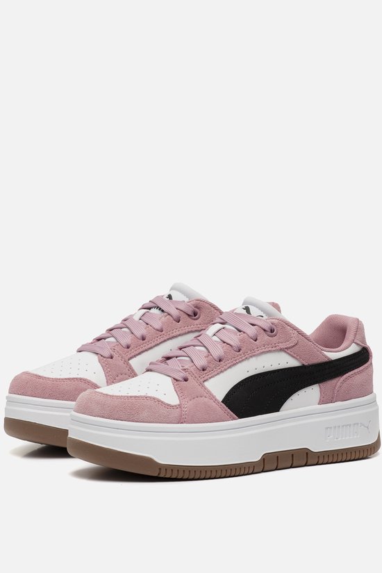 Een paar roze suède Puma sneakers met witte en zwarte accenten, op een witte plateauzool.