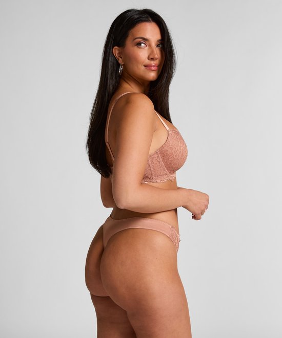 Model draagt een roze kanten bh en bijpassende string. Zijkant profiel.