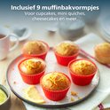 Vier rode muffinvormpjes met citroenmuffins op een schaal, naast een kop thee.