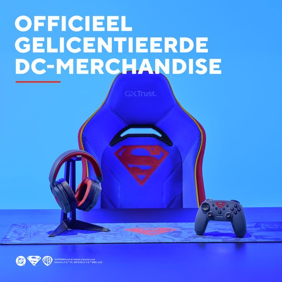 Blauwe Superman gaming stoel met rode en gele accenten en logo, naast koptelefoon en controller.