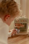 Kindje maakt koffie met een houten koffiezetapparaat in lichtgroen met houten details.