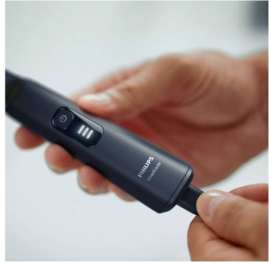 Hand die de batterij indicator toont van de Philips OneBlade Pro.