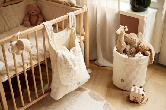 Box met crèmekleurig boxkleed en stoffen mand gevuld met knuffels.