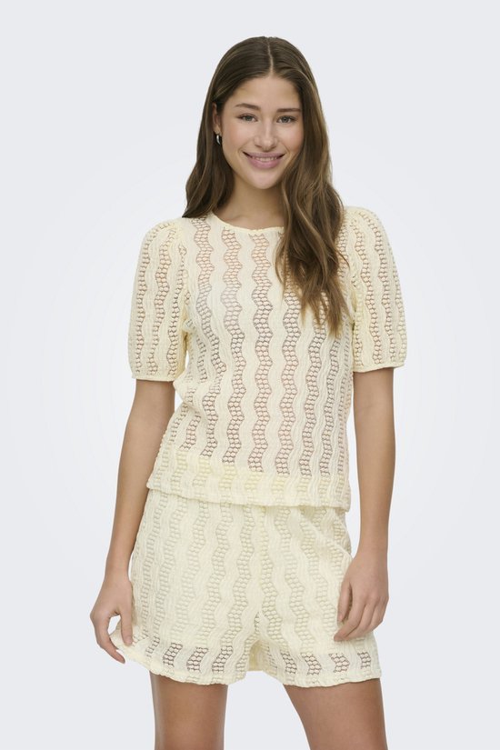 Vrouw, voorkant, draagt een crème gebreide crop top met korte mouwen en bijpassende shorts.
