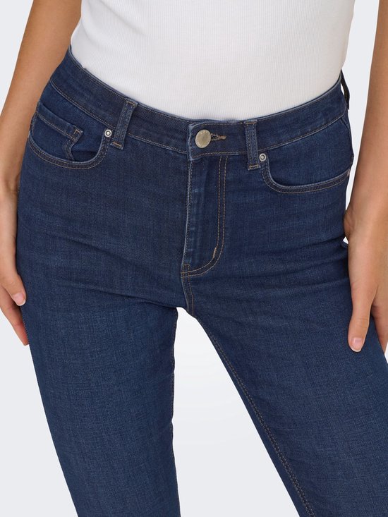 Close-up van de tailleband en zakken van een donkerblauwe skinny jeans met hoge taille.
