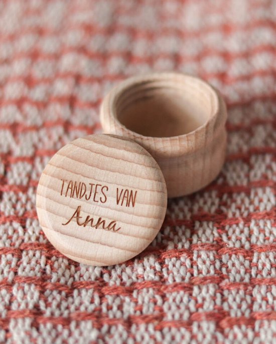 Houten melktandendoosje met de tekst "TANDJES VAN Anna" en een hartje erop, staand op een roze-witte geruite stof.