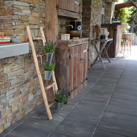 Houten decoratieve ladder met drie zilveren potten met lavendel, naast een stenen muur en houten kast.