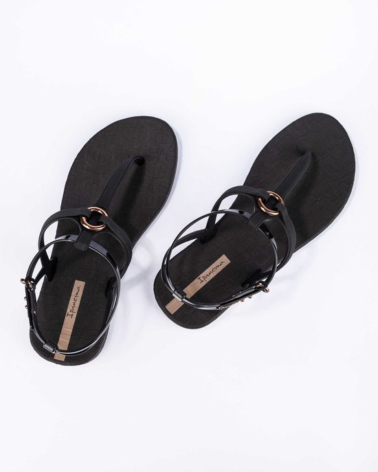 Zwarte Ipanema slippers met bandjes en gouden ringen, met subtiel patroon.