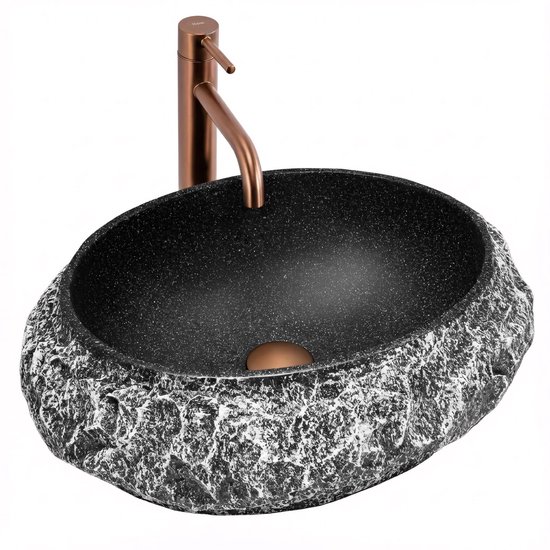 Lavabo noir en forme de pierre avec surface rugueuse et robinet en bronze.