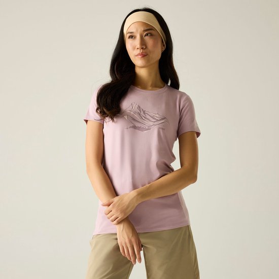 Model met een lichtroze t-shirt met korte mouwen, met een bergprint op de borst en beige hoofdband.