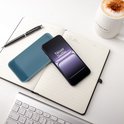 Blauw Cadorabo telefoonhoesje op een open notitieboekje, naast een smartphone en koffiemok.