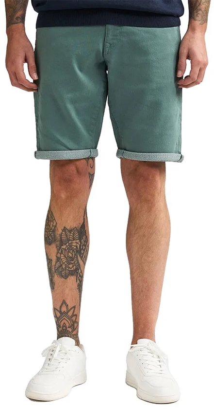 Groene slim fit stretch denim shorts met opgerolde zomen, gedragen door een model met tattoos.