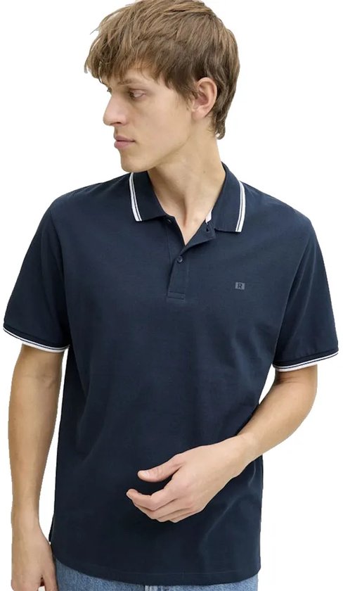 Donkerblauw poloshirt met witte strepen op de kraag en mouwen. Model draagt jeans.